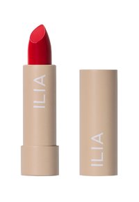 Rouge à lèvres ILIA dans un tube twist-up beige avec un bâtonnet rouge vif. Texture lisse avec une forme claire et audacieuse portant le nom de la marque imprimé.