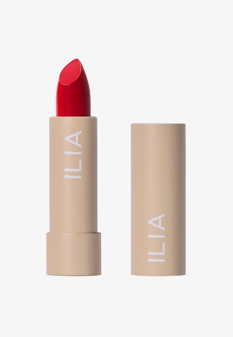 Rossetto ILIA in un tubetto beige a rotazione con una punta rossa brillante. Texture liscia con una forma chiara e audace e il nome del marchio stampato.