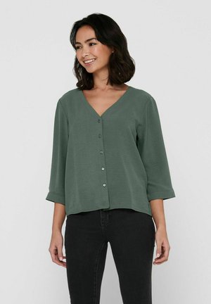 Grünes V-Ausschnitt-Shirt mit ¾-Ärmeln, das einen Knopfverschluss hat und einen lockeren Schnitt bietet. Weiche Textur mit einer glatten Oberfläche.