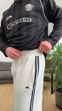 Black long-sleeve shirt with striped pattern and white accents, paired with white pants featuring navy side stripes and elastic waistband.