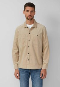 Bežová košeľa na gombíky z bavlnenej látky s golierom, dvoma náprsními vreckami a tmavými gombíkmi. Dlhé rukávy a rovný strih.