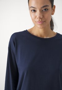 Mörkblå långärmad skjorta med rund halsringning, tillverkad av mjukt bomullstyg, med en avslappnad passform och minimala sömmdetaljer.