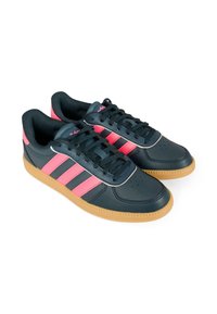 Baskets bleu marine avec trois bandes latérales roses, doublure en textile et semelle en caoutchouc naturel. Présentent un bout perforé et des lacets noirs.