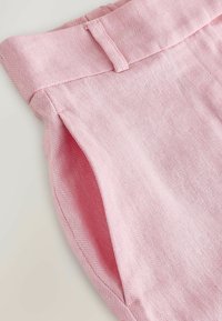 Roosad kõrge vöökohaga kohandatud püksid silmkoesooniku mustriga ja vööaasade detailiga vöökohal.