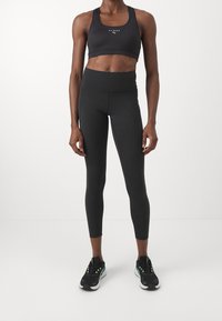 Czarny sportowy stanik i legginsy z wysokim stanem wykonane z elastycznego materiału. Charakteryzują się prostym designem, gładką fakturą i brakiem widocznych wzorów.