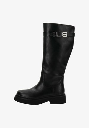 Botte en cuir noire mi-mollet avec une semelle épaisse et une sangle décorative présentant un détail métallique "4US" près du haut.