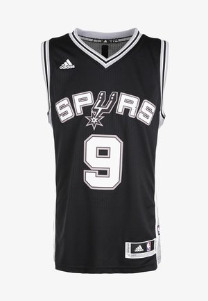 Uomo che indossa una maglia da basket nera dei San Antonio Spurs con il numero 9 e pantaloncini neri dei Brooklyn Nets, in piedi con scarpe da ginnastica bianche.
