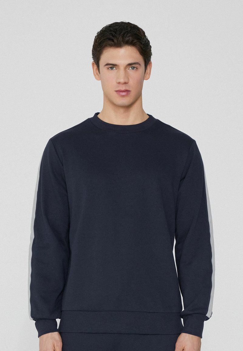 Dunkelblaue Crewneck-Sweatshirt aus Baumwollmischung, mit langen Ärmeln und kontrastierenden grauen Seitenelementen. Glatte Textur.