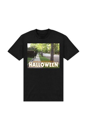 Sort t-shirt med et grafisk motiv af en gade med træer. Teksten lyder "JOHN CARPENTER'S HALLOWEEN" i fed skrift i hvidt og orange.