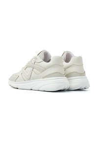 Beige sportschoenen met een gestructureerde mesh bovenkant, synthetische leren accenten en een dikke witte zool. Voorzien van vetersluiting en een gevoerde kraag.