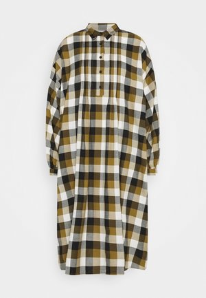 Vestido de manga larga con botones y cuello, con un corte suelto y un patrón de cuadros grandes en tonos mostaza, negro, blanco y gris.
