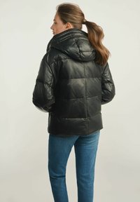 Czarna pikowana kurtka z kapturem, o błyszczącej fakturze i wzorze pikowania. Połączona z niebieskimi dżinsami, widok z tyłu.