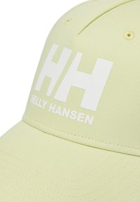 Gorra de color amarillo claro con visera curvada, tela texturizada y un logo blanco prominente que muestra "HH" y "HELLY HANSEN" en el frente.
