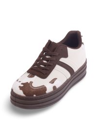 Baskets blanches avec des accents marron et un imprimé vache. Présentent un bout rond, une semelle plate et un design à laçage à six œillets. Fabriquées en tissus doux et matériaux synthétiques.