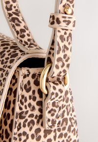 Handtas met luipaardprint, beige basis, gouden details en een gestructureerde vorm. De schouderriem heeft een textuur en een zichtbare gesp.