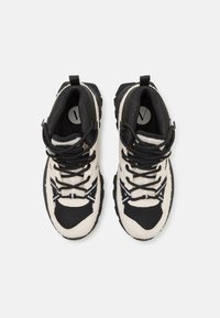 Schwarze und cremefarbene Laufschuhe mit strukturiertem Stoff und Mesh-Details, ausgestattet mit schwarzen Schnürsenkeln und einem auffälligen Gummisohlen-Design.