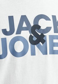 Hvid bomulds T-shirt med stort blåt tekst og en mørkeblå ampersand. Designet inkluderer brandnavnet "JACK & JONES" tydeligt vist.