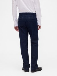 Σκούρες μπλε τζιν παντελόνια με ίσια γραμμή, που διαθέτουν δύο πίσω τσέπες, θηλιές για ζώνη και καθαρό τελείωμα στα μανίκια.