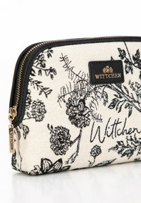 Zwart-wit bloemenprint cosmeticazak met gouden hardware, ritsluiting en een logo patch. Gemaakt van duurzame stof met een gestructureerde afwerking.