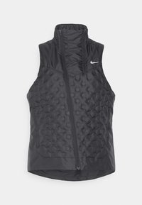 Chaleco negro sin mangas con un cuello alto, que presenta una textura acolchada y una cremallera frontal. Logo de Nike en blanco en la parte superior izquierda.