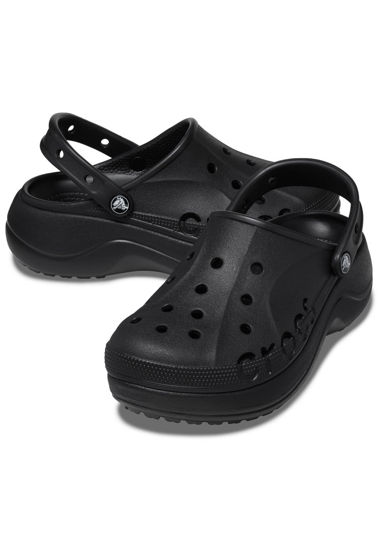 Zuecos de goma negra con agujeros de ventilación, una correa trasera y suela texturizada. Presentan un logotipo en relieve en el lateral y un borde ligeramente elevado.