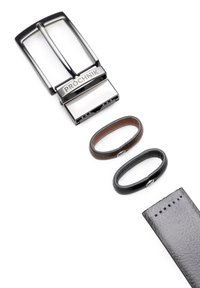 Metalowa klamra paska z podwójnymi zębami oznaczona "PROCHNIK", w komplecie z dwiema skórzanymi pętlami—jedną brązową, drugą czarną—i fakturowanym czarnym paskiem.