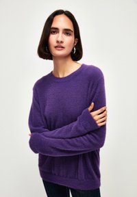 Lila, flauschiger Pullover aus weichem Material mit langen, weiten Ärmeln und einer lässigen Passform. Strukturierte Oberfläche mit Rundhalsausschnitt.