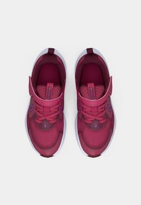 Scarpe sportive di un rosa intenso con tessuto a rete, interni imbottiti, dettagli viola e una cinghia a strappo per una vestibilità sicura.
