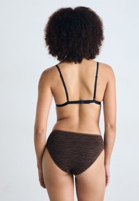 Brown patterned underwear with a high-waisted design, featuring black tiger stripe accents and adjustable black straps on the back.