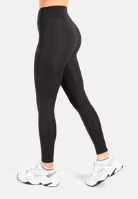 Zwart, high-waisted legging gemaakt van glad, rekbaar materiaal, met een aansluitend ontwerp en naadloze constructie voor comfort en flexibiliteit.