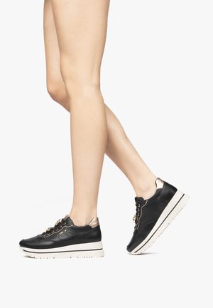 Black leather sneakers with a white sole, gold accents on the laces, and a metallic heel detail. The design features a low profile.