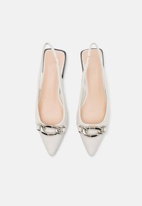 Talons aiguilles blanche avec bride arrière, texture mate, accent de chaîne argentée et capuchon de talon noir. Semelle intérieure beige lisse avec logo en relief.