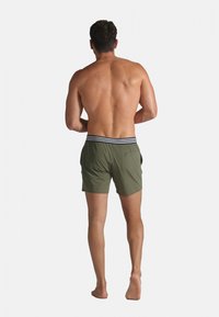 Shorts de bain pour hommes de couleur vert olive avec une ceinture élastique rayée et des poches latérales, vus de dos, longueur au-dessus du genou.