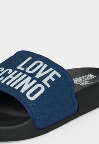 Σανδάλι slide με ανοιχτό δάχτυλο, παχύ μαύρο πάτο και μπλε υφασμάτινο λουράκι με λευκό κείμενο "LOVE MOSCHINO".