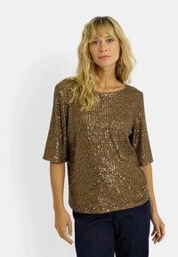 Top de lentejuelas bronce con un corte relajado, mangas cortas y textura de canalé. Superficie suave con acabados brillantes que reflejan la luz.