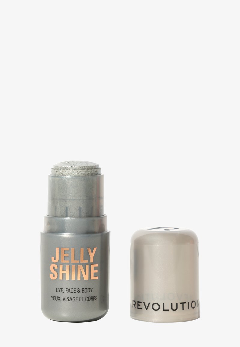Iluminador Jelly Shine en envase gris con una tapa brillante. El texto incluye "JELLY SHINE" y "OJO, CARA Y CUERPO" en naranja y gris.