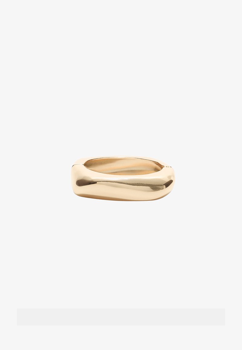 Anello dorato caratterizzato da un design liscio e arrotondato con una forma leggermente attorcigliata. La finitura lucida mette in risalto le curve sinuose.