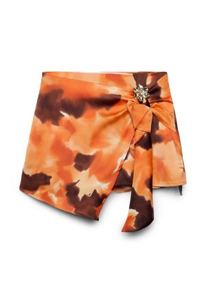Gonna a portafoglio tie-dye arancione e marrone con orlo asimmetrico, legata lateralmente con un accessorio dorato a forma di fiore.