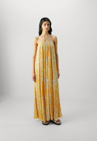 Vestido maxi en amarillo y blanco con un patrón ondulado, hecho de tela ligera. Presenta tirantes de spaghetti ajustables y una silueta fluida.