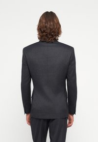 Mørk grå dressjakke med skreddersydd passform, glatt tekstur, strukturerte skuldre og tre-knappsdetalj på ermene. Enkel design bak.