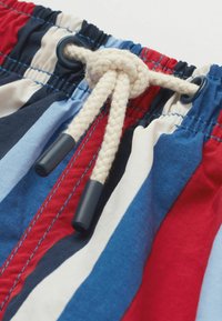 Costume da bagno a righe con tessuto blu, rosso e bianco, vita elastica e cordino intrecciato con punte in plastica.