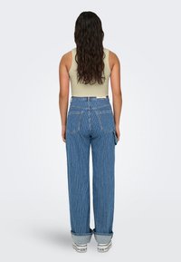 Blauwe en witte gestreepte denim jeans met een losse pasvorm, hoge taille en omgeslagen zoom, gecombineerd met een beige strak tanktop.