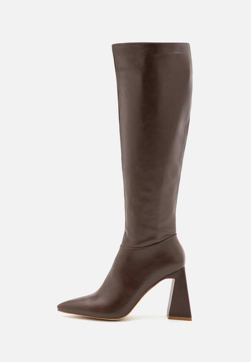 Botte haute en cuir marron avec bout pointu et talon carré large sur fond blanc, vue de côté.