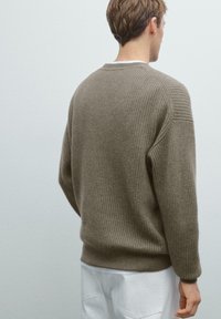 Khaki geribbelde trui met een ronde hals en verticale textuur, met drop shoulders en een ontspannen pasvorm. Zacht gebreid materiaal.