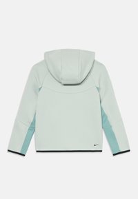 Ανοιχτό πράσινο φούτερ με μεγάλη κουκούλα, αντίθετες τιρκουάζ πλευρές και μαύρο τελείωμα. Λογότυπο Nike σε μαύρο χρώμα στο κάτω δεξί μέρος.