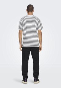 Korte ærmer t-shirt i bomuld med vandrette sort-hvide striber, parret med sorte cargobukser med sidelommer.