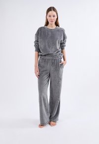 Szary, teksturowany zestaw odzieży domowej składający się z prążkowanego swetra z marszczonymi rękawami oraz spodni z szerokimi nogawkami, elastycznym paskiem i kieszeniami.