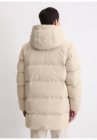 Beige donsjack met capuchon, met een doorgestikt ontwerp, zachte textuur en een knielengte. Geen zichtbare accessoires of patronen.