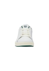 Sneaker alb cu accente verzi, superior din piele netedă, laterale perforate, șireturi albe și talpă din cauciuc. Logo pe limba pantofului. Formă a vârfului rotunjită.