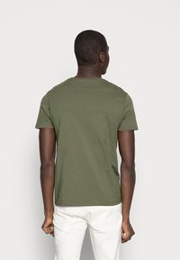 Olivgrünes T-Shirt mit kurzen Ärmeln und Rundhalsausschnitt. Hergestellt aus weicher Baumwolle, hat eine schlichte Textur und einen lässigen Schnitt. Rückansicht gezeigt.